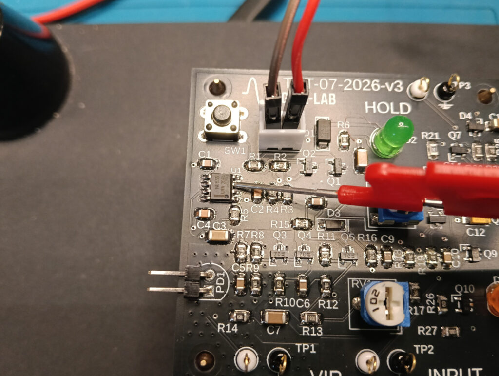Puntale dell'oscilloscopio collegato al nodo OUT_NE555 sulla PCB GX-TXT-v3 per misurare la durata della temporizzazione.