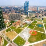 Vista aerea del parco Biblioteca degli Alberi a Milano, con i prati e i percorsi pedonali in primo piano, il Bosco Verticale a sinistra e i grattacieli di Porta Nuova sullo sfondo
