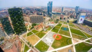 Vista aerea del parco Biblioteca degli Alberi a Milano, con i prati e i percorsi pedonali in primo piano, il Bosco Verticale a sinistra e i grattacieli di Porta Nuova sullo sfondo